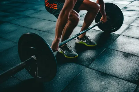 An athlete preparing to lift a barbell in a gym